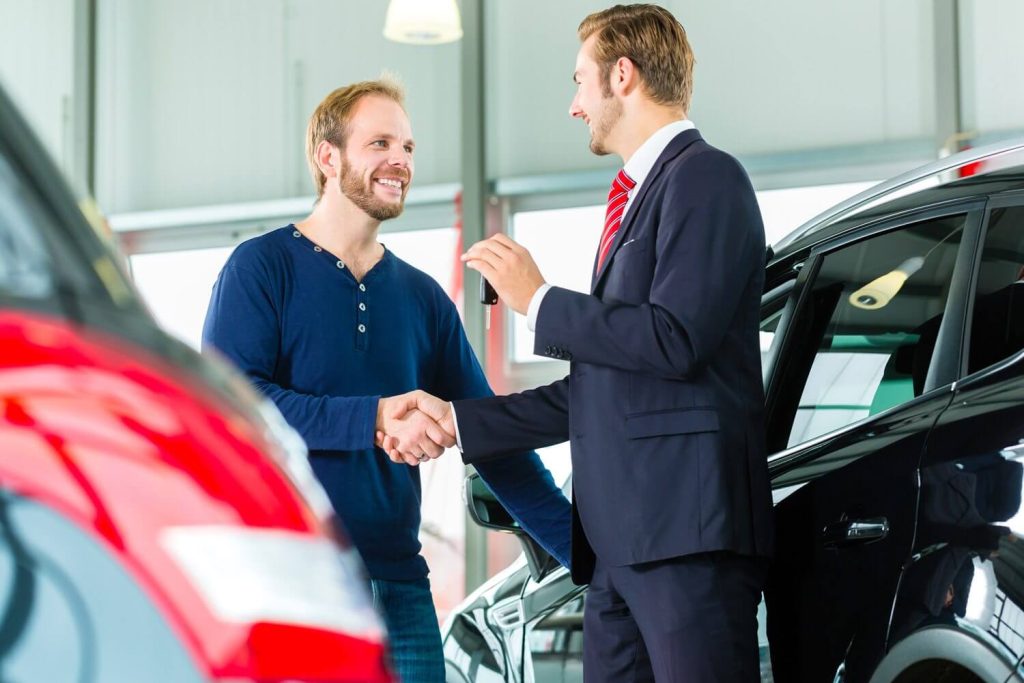 Smiling customer shakes hands with an auto body shop service advisor, confirming professional vehicle collision repair.