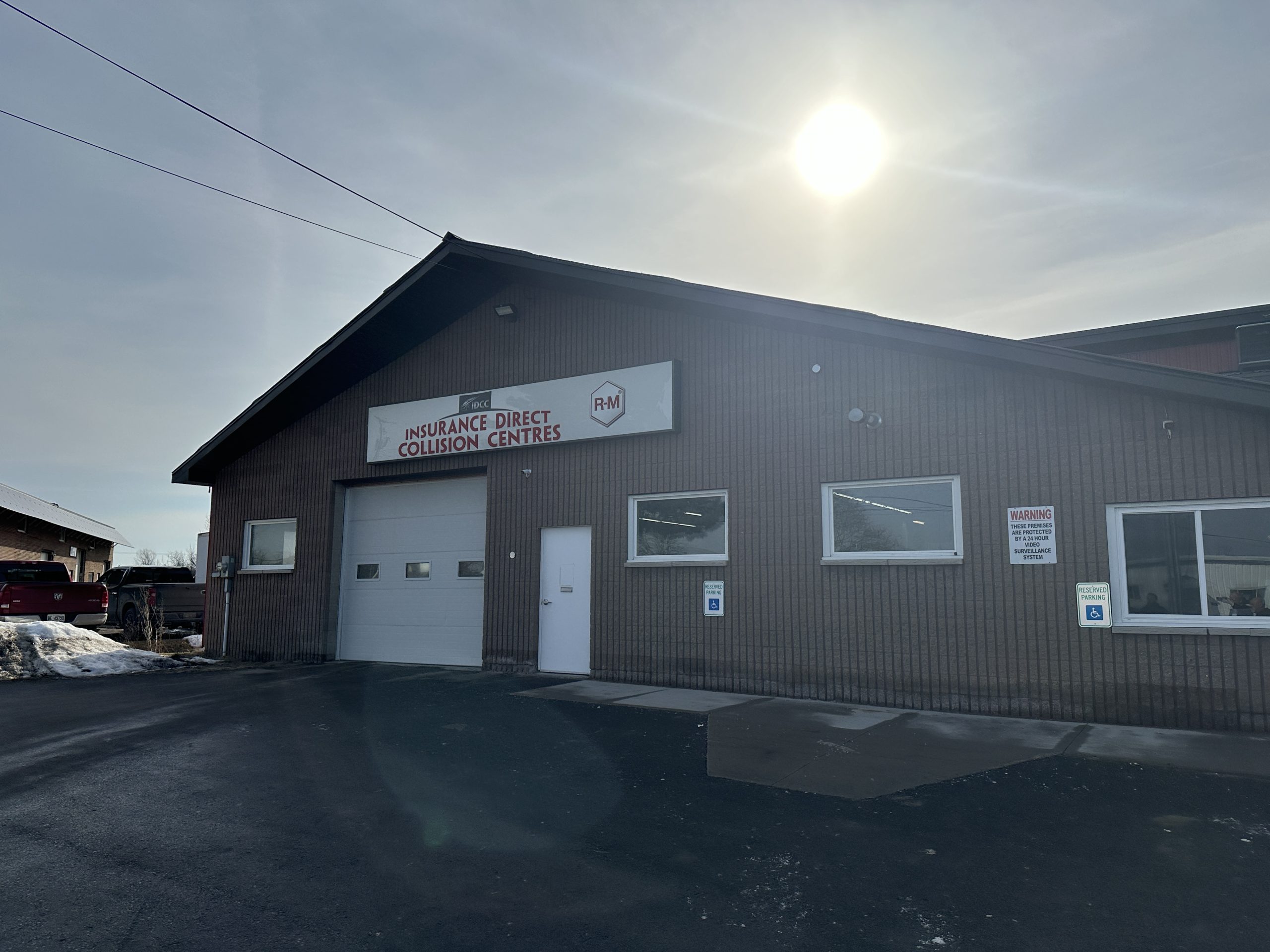 Front exterior view of P & D Auto Body & Collision Repair Center, a brown auto body repair shop with a large garage door.